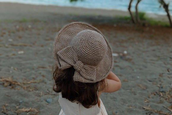 Crochet Coquette Sun Hat — crochet bucket hat patterns Crochet Coquette Sun Hat in a natural color on a child at the beach — crochet bucket hat patterns