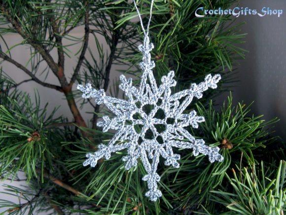 Crochet Snowflake Ornament — Crochet Christmas Ornaments Patterns Crochet Christmas snowflake ornament hanging on a pine tree branch. — Crochet Christmas Ornaments Patterns