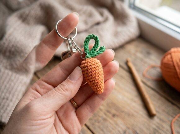Mini Crochet Carrot Keyring — crochet Easter patterns Miniature crochet carrot keyring with green top held in hand near window — crochet Easter patterns