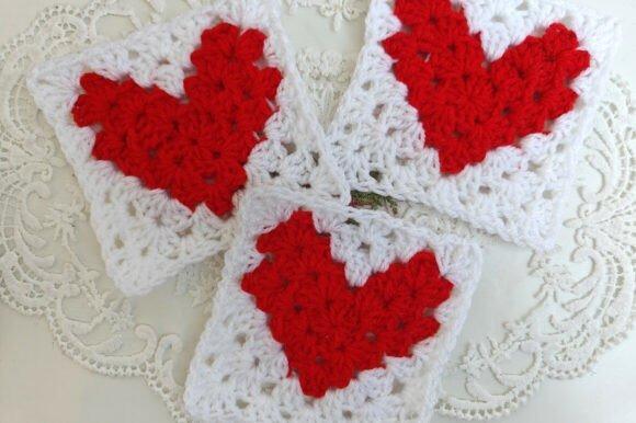 Pixel Heart Granny Square — Valentine crochet patterns Three white granny squares each with a red heart motif crocheted in the center on a lace — Valentine crochet patterns