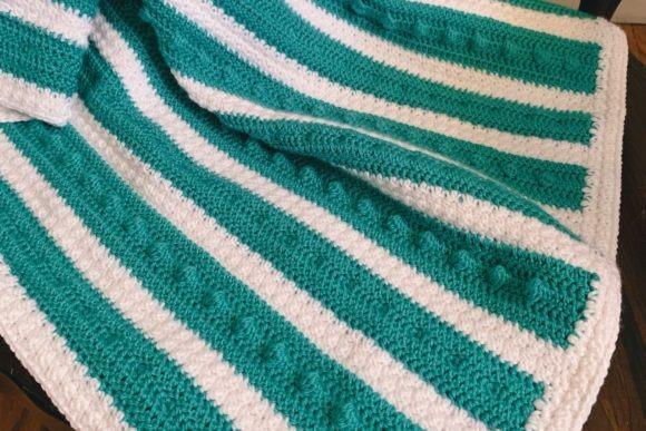 Double Trouble Bobble Baby Blanket — cozy crochet blanket patterns Cozy crochet blanket patterns featuring a bobble texture in teal and white stripes.