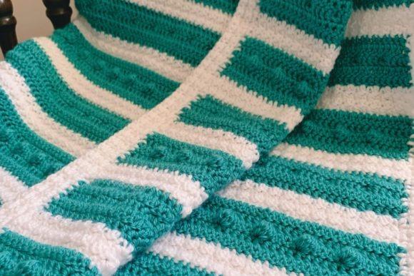 Double Trouble Bobble Baby Blanket — cozy crochet blanket patterns Cozy crochet blanket patterns featuring bobble texture in teal and white stripes.