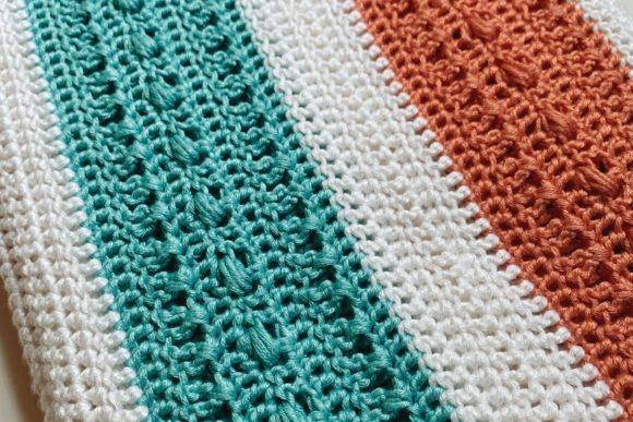 Sara Bead Baby Blanket — cozy crochet blanket patterns Cozy crochet blanket patterns featuring a textured design in teal, white, and orange stripes.