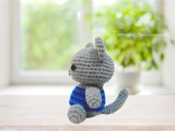 Cute Animal Amigurumi Cat — Cute Animal Amigurumi Patterns Cute Animal Amigurumi Patterns featuring a small crocheted gray cat wearing a blue T-shirt sitting on a wooden surface