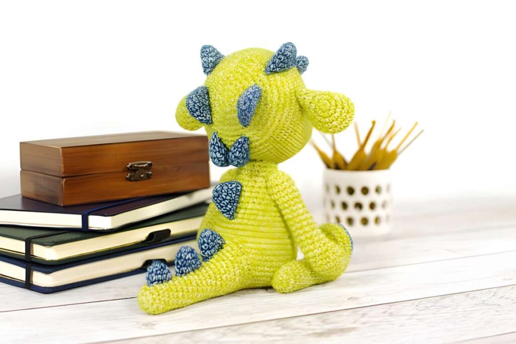 Amigurumi crochet dragon pattern showcasing a green dragon with blue spikes. — amigurumi crochet patterns