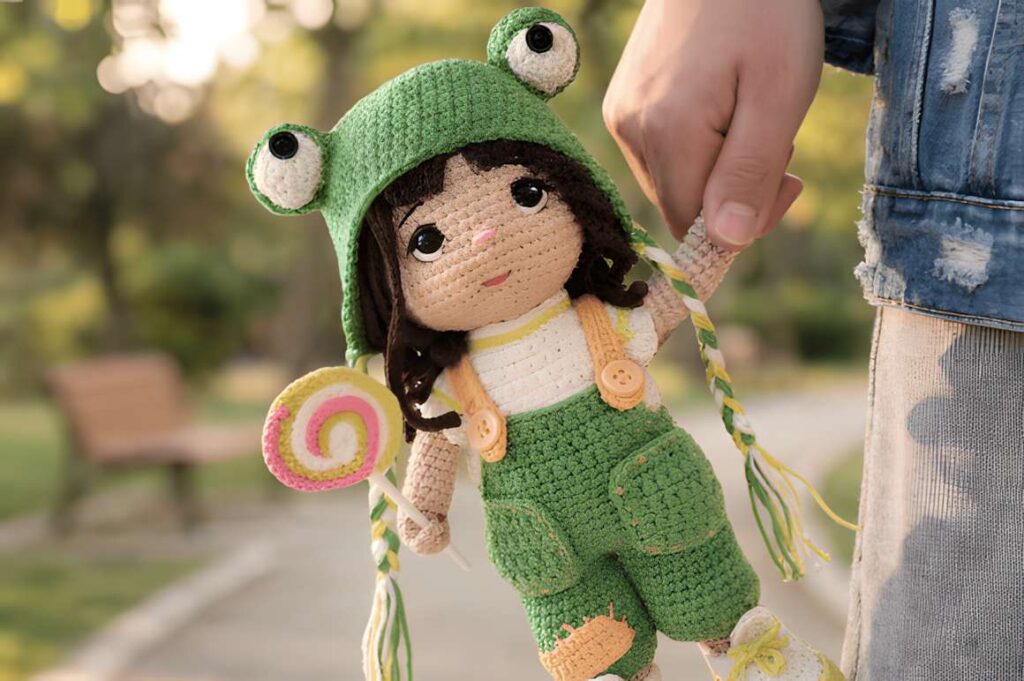 Frog Hat Doll Crochet Pattern featuring a doll with a frog-themed hat, ideal for amigurumi crochet patterns.